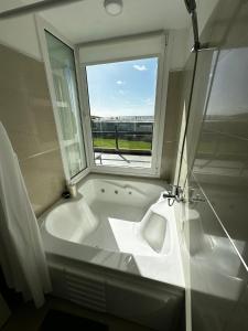 y baño con ventana y bañera blanca. en Linda Bay Spa Apartments, en Mar de las Pampas