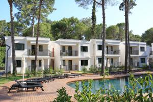 ein Gebäude mit einem Pool, Bäumen und Bänken in der Unterkunft Siu Collection - Ultra All Inclusive in Beldibi