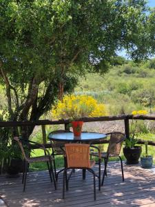 una mesa y sillas en una terraza con flores en Armonía en Villa Serrana