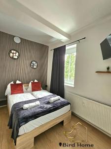 a bedroom with a bed with red pillows and a window at Bird Home Room 11 in Klagenfurt