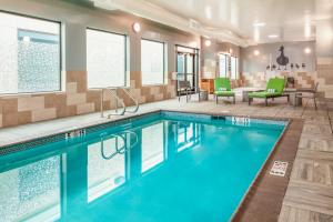 a pool in a hotel room with chairs and tables at Homewood Suites By Hilton Belmont in Belmont