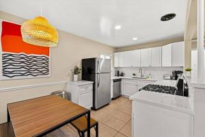 a kitchen with white cabinets and a table and a refrigerator at 2 bedroom with bunk room and private yard for pets in Santa Barbara