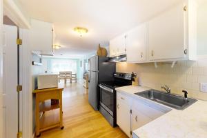 a kitchen with white cabinets and a stainless steel refrigerator at Sea View Revue - A in Dennis Port