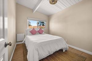 a white bedroom with a bed with pink pillows at New 2 Bed Apartment Close to Downtown and Beach in Santa Barbara