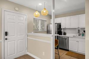 a kitchen with white cabinets and a white door at Brand New Apartment Close to Beach and Downtown in Santa Barbara