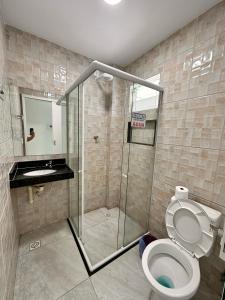 a bathroom with a toilet and a glass shower at Pousada Diamante in Ubajara