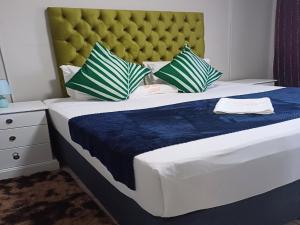 a bedroom with a large bed with a blue blanket and pillows at TOP TOWN LODGE in Butterworth