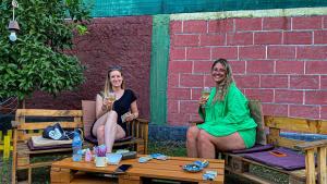 two women sitting on chairs on a patio with drinks at The Hood - Shkodra Backpackers Hostel in Shkodër