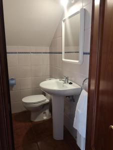 een badkamer met een toilet, een wastafel en een spiegel bij Viviendas Vacacionales Beni II in Llanes