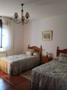 1 dormitorio con 2 camas y lámpara de araña en Viviendas Vacacionales Beni II, en Llanes