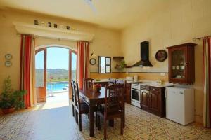 una cucina con tavolo e una sala da pranzo di 3 Bedroom Farmhouse with Private Pool & Views a Għajnsielem