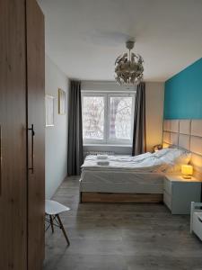 sypialnia z łóżkiem, oknem i żyrandolem w obiekcie Apartament Paderewskiego w Kielcach
