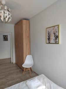 1 dormitorio con silla blanca y armario en Apartament Paderewskiego, en Kielce