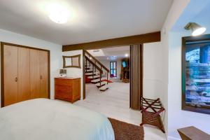 a bedroom with a white bed and a staircase at Mid-Century Cabin Creekside, Easy Access to i-70 in Dumont