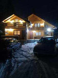 dom z dwoma samochodami zaparkowanymi na śniegu w nocy w obiekcie Ski Chalet Jahorina w mieście Jahorina