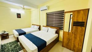 1 dormitorio con 2 camas y puerta de madera en Mystique Inn Wayanad en Vythiri