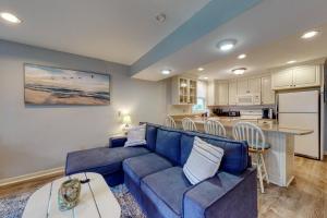 uma sala de estar com um sofá azul e uma cozinha em Long Sands Escape em York