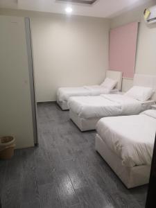 three beds in a room with white walls at هلتون بلو in Makkah