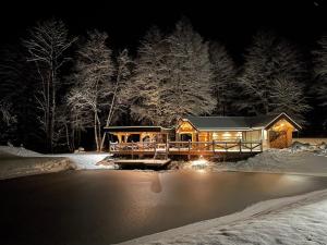 una cabaña de madera en la nieve por la noche en Gervės dvaro svečių namelis en Vėžionys