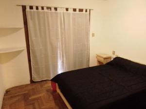 ein Schlafzimmer mit einem Bett und einem Fenster mit einem Vorhang in der Unterkunft Casa grande en Mar del Plata, cochera, parrilla, parque, TV con wifii. IMPECABLE in Mar del Plata