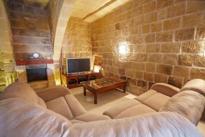 a living room with a couch and a tv at 5 Bedroom Farmhouse with Private Pool & Views in Għarb