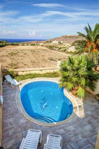 a swimming pool with two lounge chairs and the ocean at 5 Bedroom Farmhouse with Private Pool & Views in Għarb