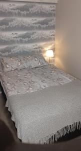 ein Bett mit einer weißen Bettdecke und einer Lampe in der Unterkunft Lapland winter cottage in Rovaniemi