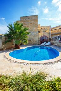 une grande piscine avec deux chaises en face d'un bâtiment dans l'établissement 5 Bedroom Farmhouse with Private Pool & Views, à L-Għarb