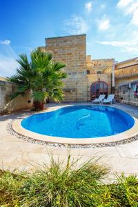 a large swimming pool with two chairs in front of a building at 5 Bedroom Farmhouse with Private Pool & Views in Għarb