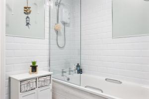 a white bathroom with a tub and a shower at Ballycastle Bolthole in Ballycastle
