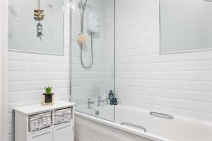 Un baño blanco con bañera y ducha. en Ballycastle Bolthole, en Ballycastle