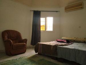 ein Schlafzimmer mit einem Bett, einem Stuhl und einem Fenster in der Unterkunft ParadisPlage, 1 min de la mer in Saly Portudal