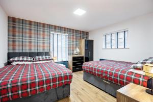 a bedroom with two beds and a table and two windows at Ballycastle Bolthole in Ballycastle