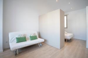 una silla blanca con 2 almohadas en una habitación en BcnStop Sant Pau Suites, en Barcelona