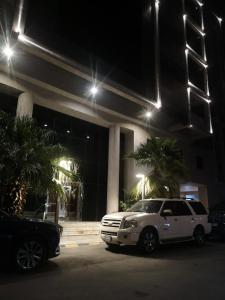 Un todoterreno blanco estacionado frente a un edificio por la noche en هلتون بلو en La Meca