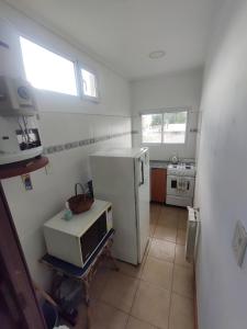 a small kitchen with a white refrigerator and a window at Monoambiente Centrico Pihue in Pigüé