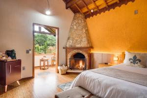 a bedroom with a large bed and a fireplace at Pousada Jardim Monte Verde in Monte Verde
