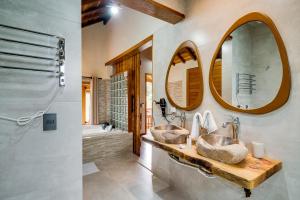 two sinks in a bathroom with two mirrors at Pousada Jardim Monte Verde in Monte Verde
