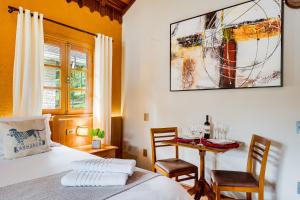 a bedroom with a bed and a table with chairs at Pousada Jardim Monte Verde in Monte Verde