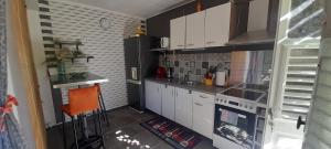 a small kitchen with white cabinets and an orange chair at Le LiloVert - Studio 24 m2 in Le Carbet