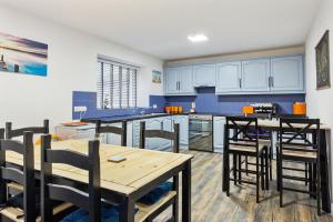 una cocina con armarios azules y una mesa y sillas de madera. en Ballycastle Bolthole, en Ballycastle