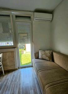 uma sala de estar com um sofá e duas janelas em Oaza mira em Osijek