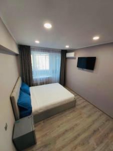 Schlafzimmer mit einem Bett und einem Flachbild-TV in der Unterkunft Светлые апартаменты- Афины in Almaty