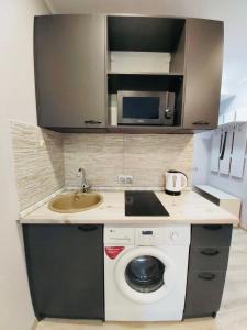a kitchen with a sink and a washing machine at Светлые апартаменты- Афины in Almaty