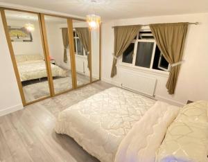 - une chambre avec un grand lit et un grand miroir dans l'établissement Watford cottage holiday house, à Abbots Langley