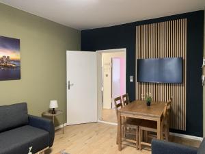 ein Wohnzimmer mit einem Tisch, einem Sofa und einem TV in der Unterkunft Just Berlin - Wohnung für bis zu 12 Personen in Berlin