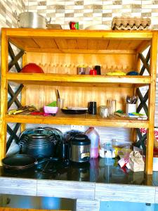 a wooden shelf with pots and pans on it at Tin apartment Tanga in Tanga