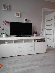 a white entertainment center with a flat screen tv on it at LesnApart in Hel