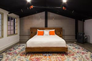 1 dormitorio con 1 cama con almohadas de color naranja sobre una alfombra en Petaluma Warehouse Lofts unit E en Petaluma