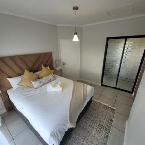 a bedroom with a large bed with white sheets and pillows at Prunell in midrand in Midrand